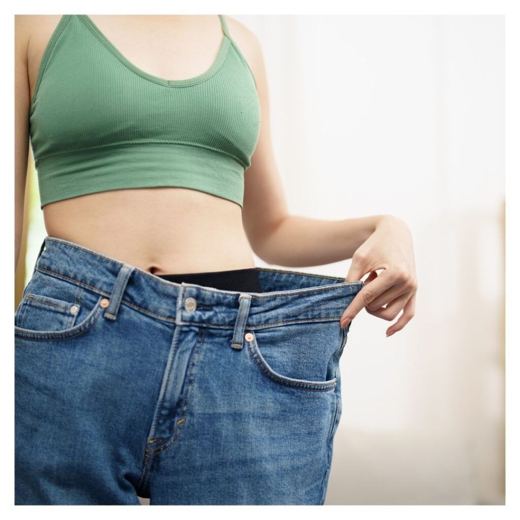 a women stretching her pants to show off her weight loss